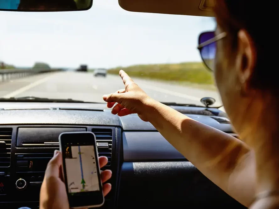 Žena naviguje v autě pomocí telefonu