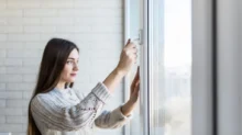 Žena otevírá okno, aby vyvětrala