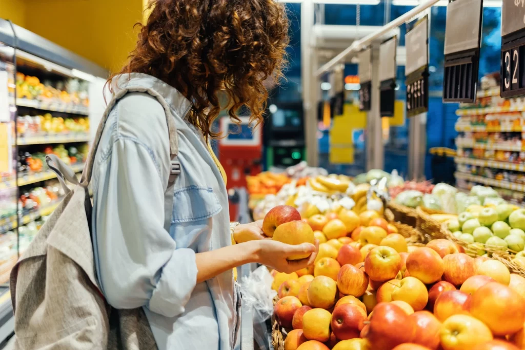 Citrusy obsahují mnoho vitamínů. Zdroj: Shutterstock - Techsvět žena sahá v supermarketu na pomeranč