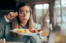žena zkoumá své jídlo pod lupou