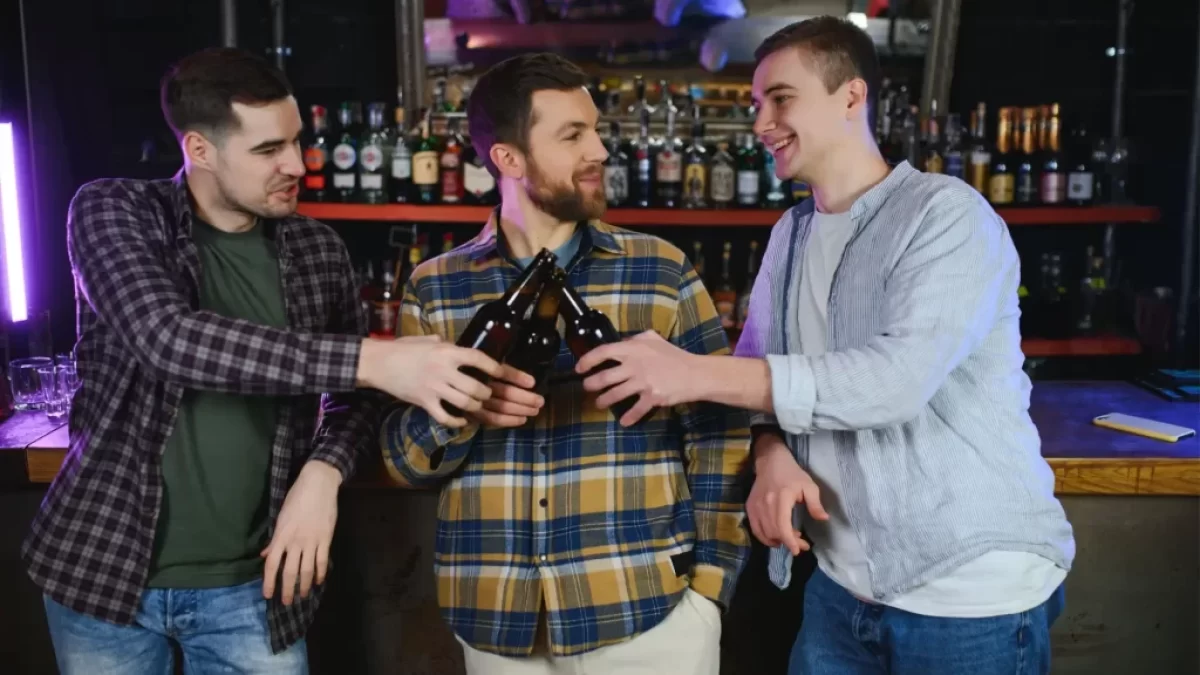tři muži na baru pijí pivo