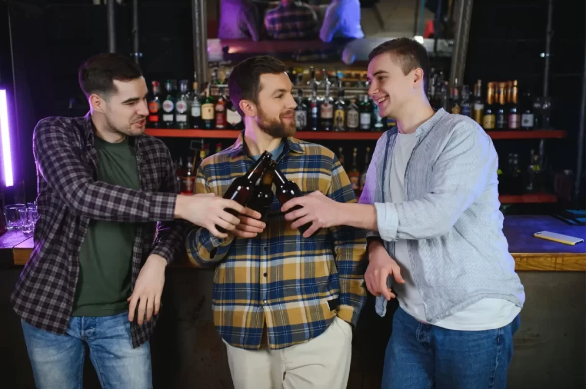 tři muži na baru pijí pivo