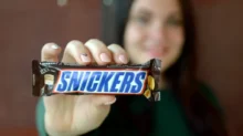 žena drží tyčinku Snickers