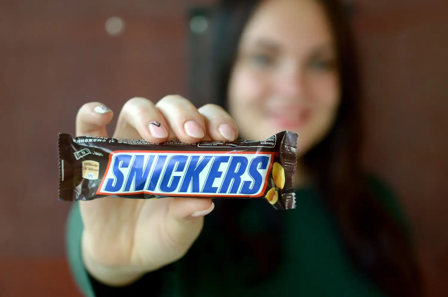 žena drží tyčinku Snickers