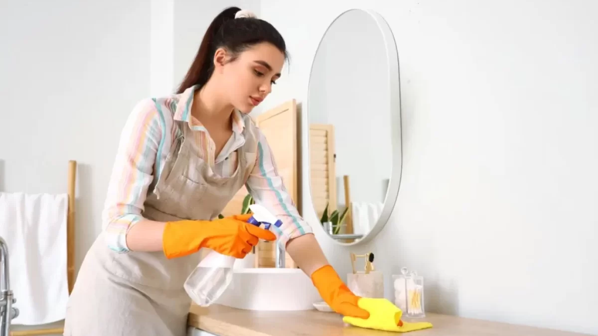 Žena utírá prach v domácnosti