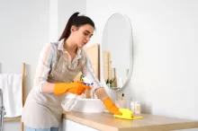 Žena utírá prach v domácnosti