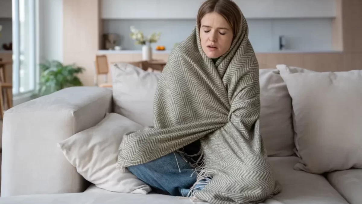Žena sedící na gauči je zabalená do deky