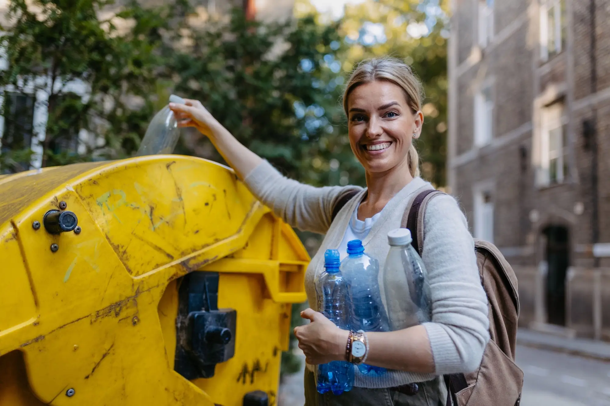 Žena vyhazuje plast do kontejneru
