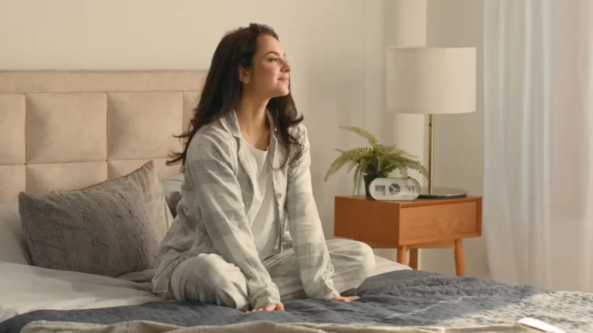 Spokojená žena sedí na posteli v ložnici