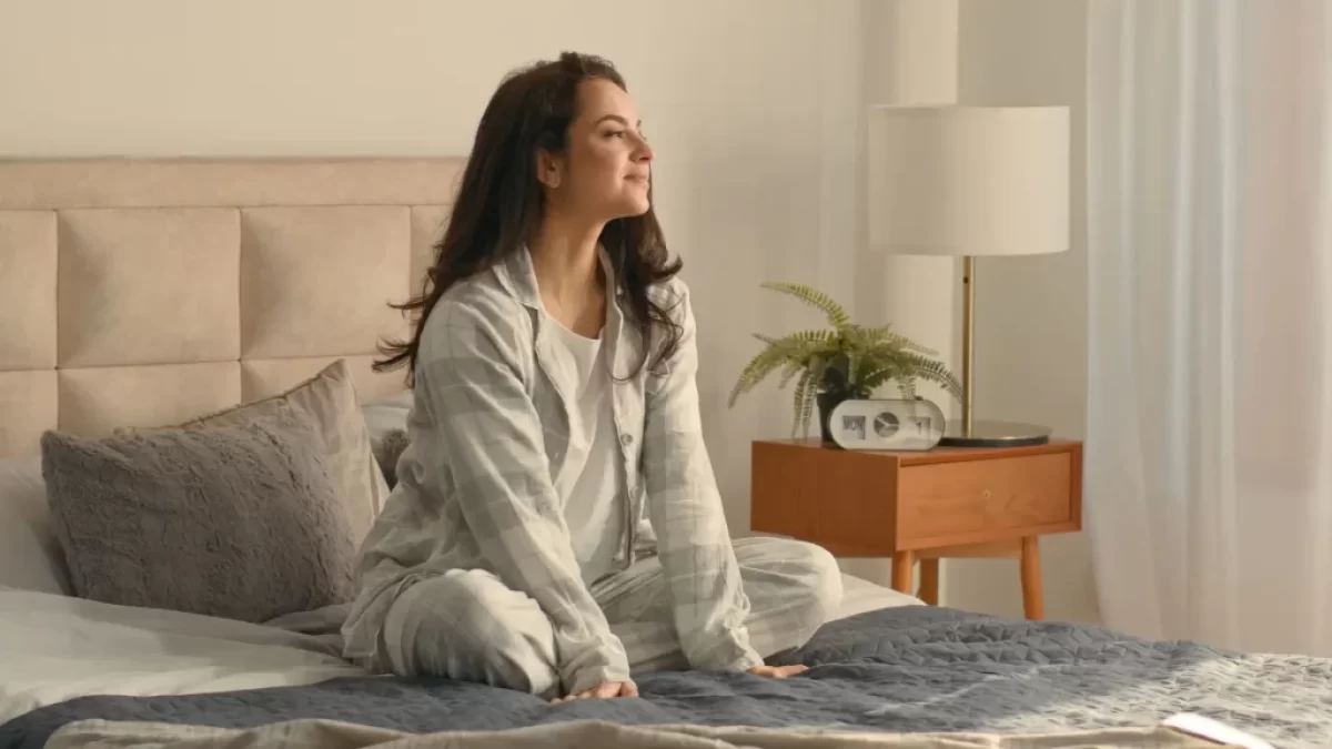 Spokojená žena sedí na posteli v ložnici