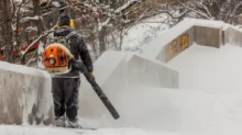 Muž odfoukává sníh fukarem