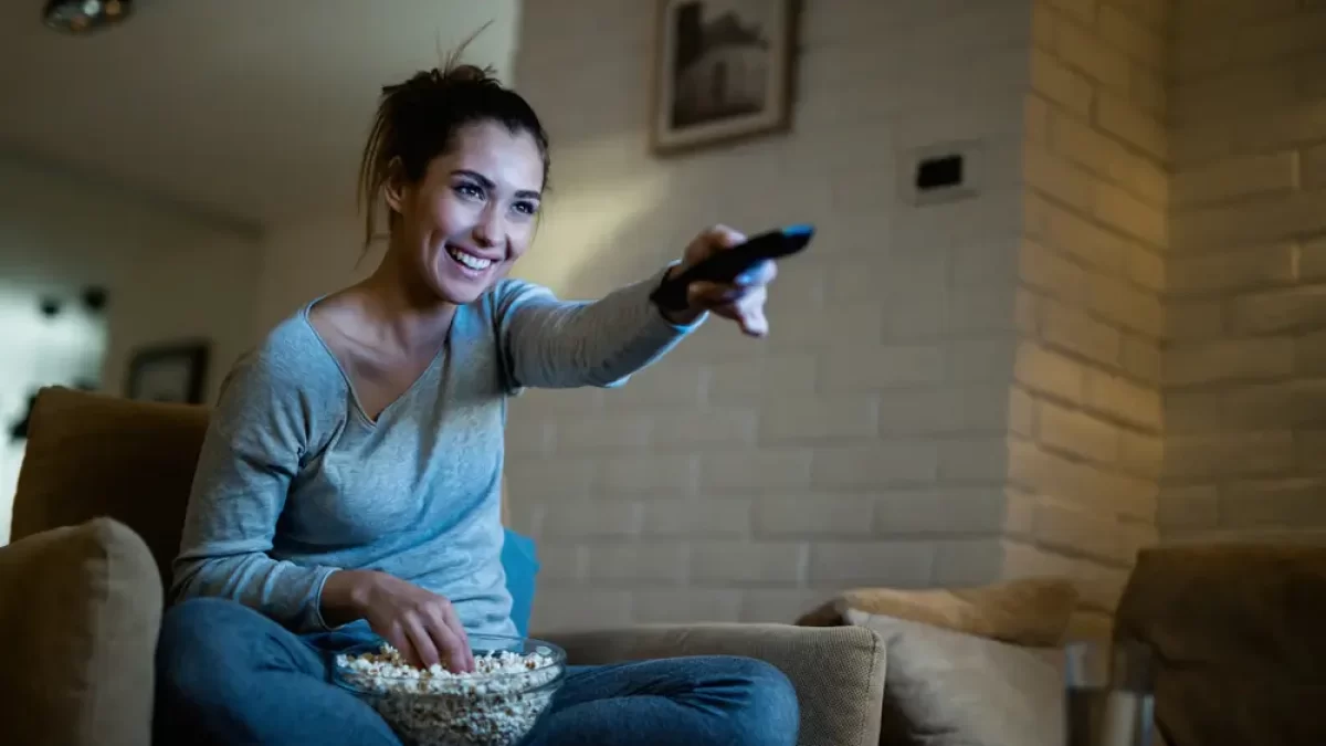 Žena pouští ovladačem televizi