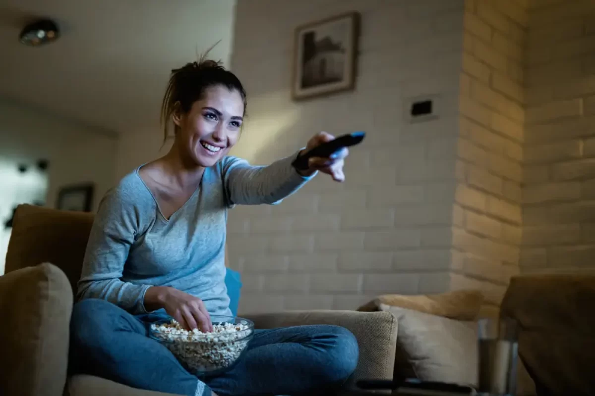Žena pouští ovladačem televizi