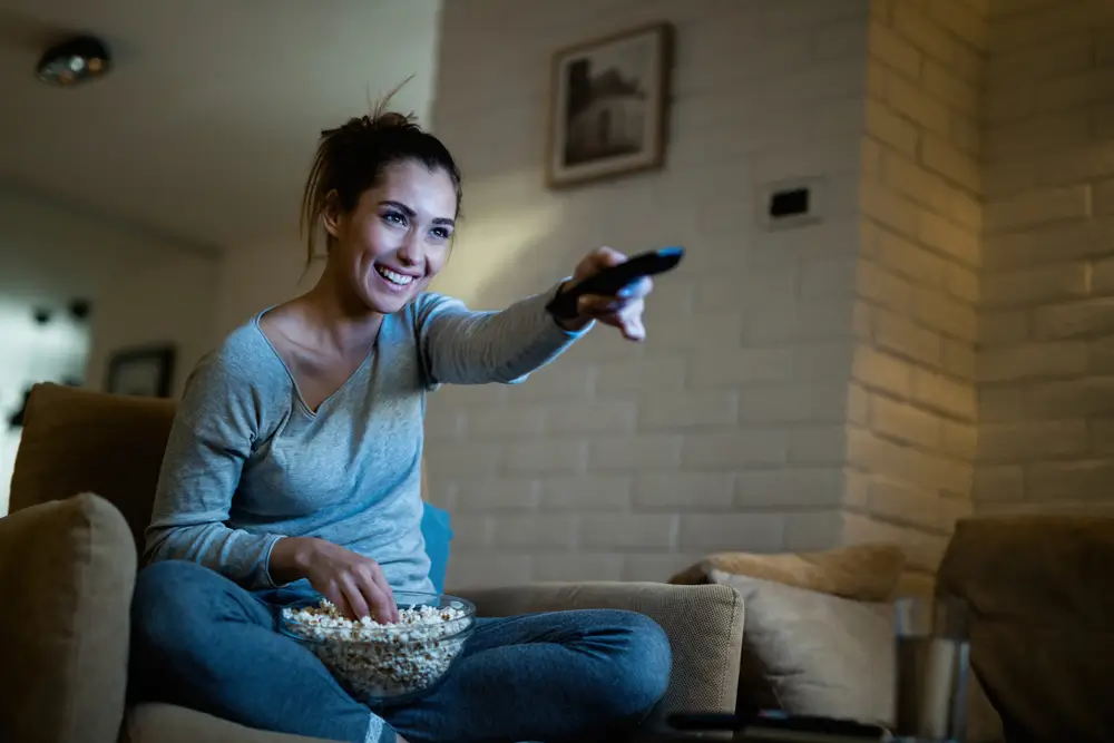 Žena pouští ovladačem televizi