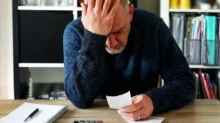 Muž má hlavu v dlaních a čte účet za elektřinu