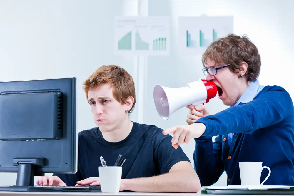 muž křičí do megafonu na jiného muže