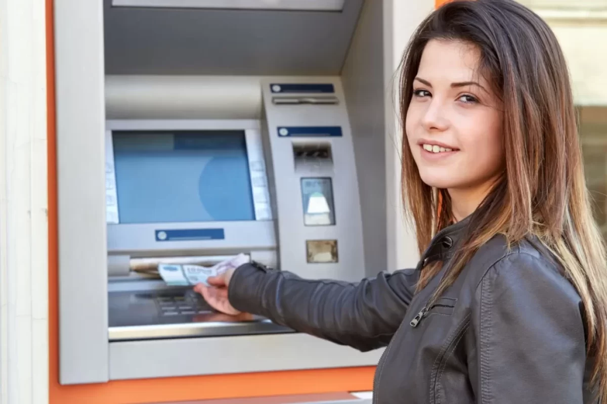 Žena vybírá peníze z bankomatu