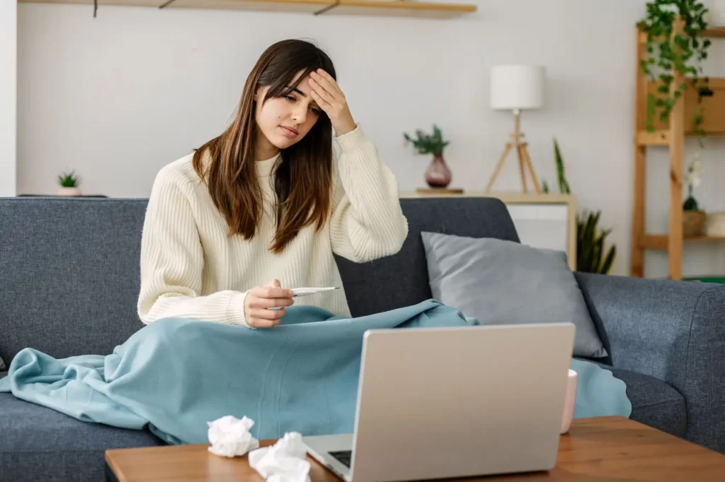 Na nemocenskou mají nárok i OSVČ. Málokdy si ale pojištění platí, a tak musí často pracovat i v nemoci, FOTO: Shutterstock - Techsvět Nemocná žena sedí u počítače