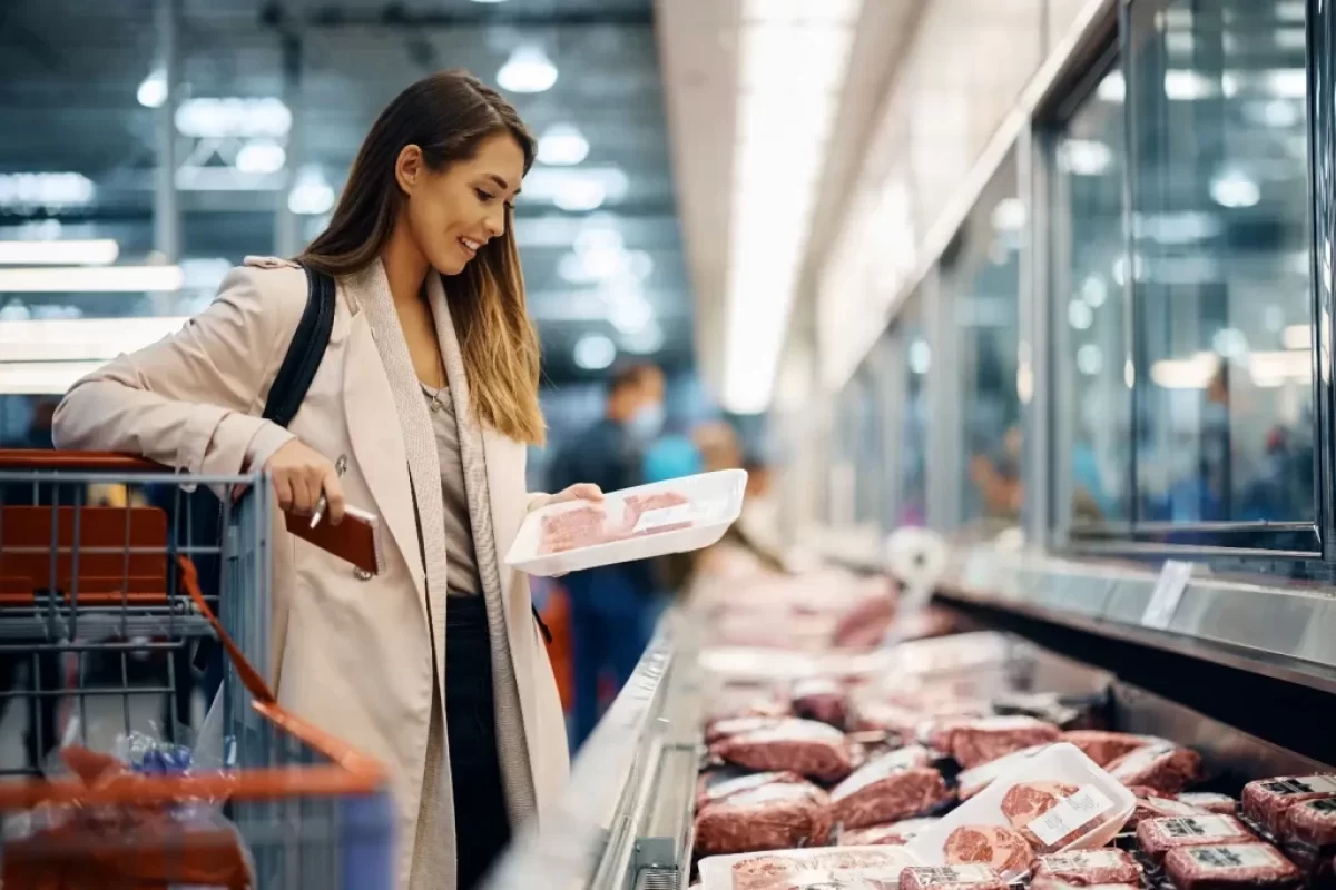 žena si v supermarketu vybírá maso