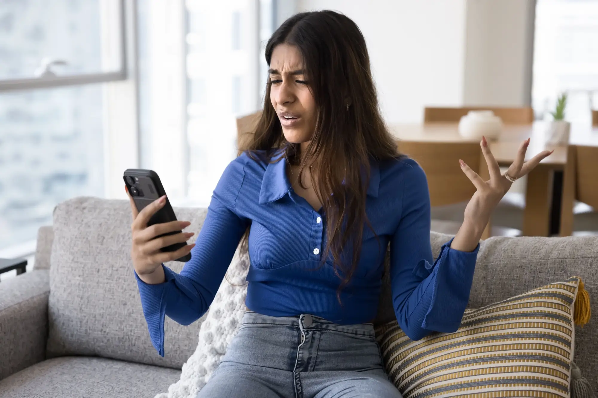 Žena nevěřícně kouká na telefon