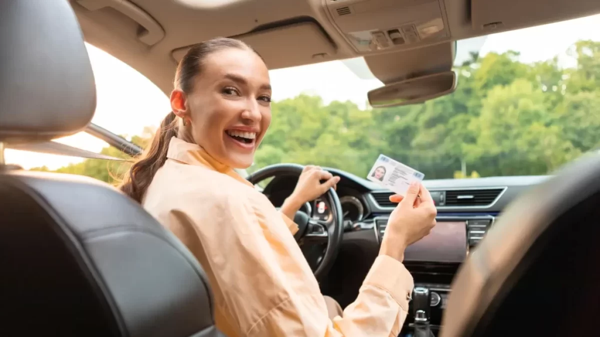 Žena v autě drží řidičský průkaz