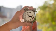 Muž posouvá hodinovou ručičku zpět