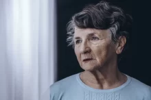 starší žena s problémy s pamětí hledí z okna