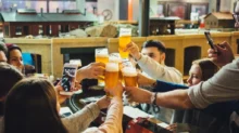Lidé v hospodě si připíjejí pivem.
