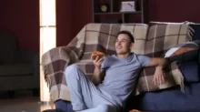 Muž se v noci dívá na televizi a jí u toho pizzu