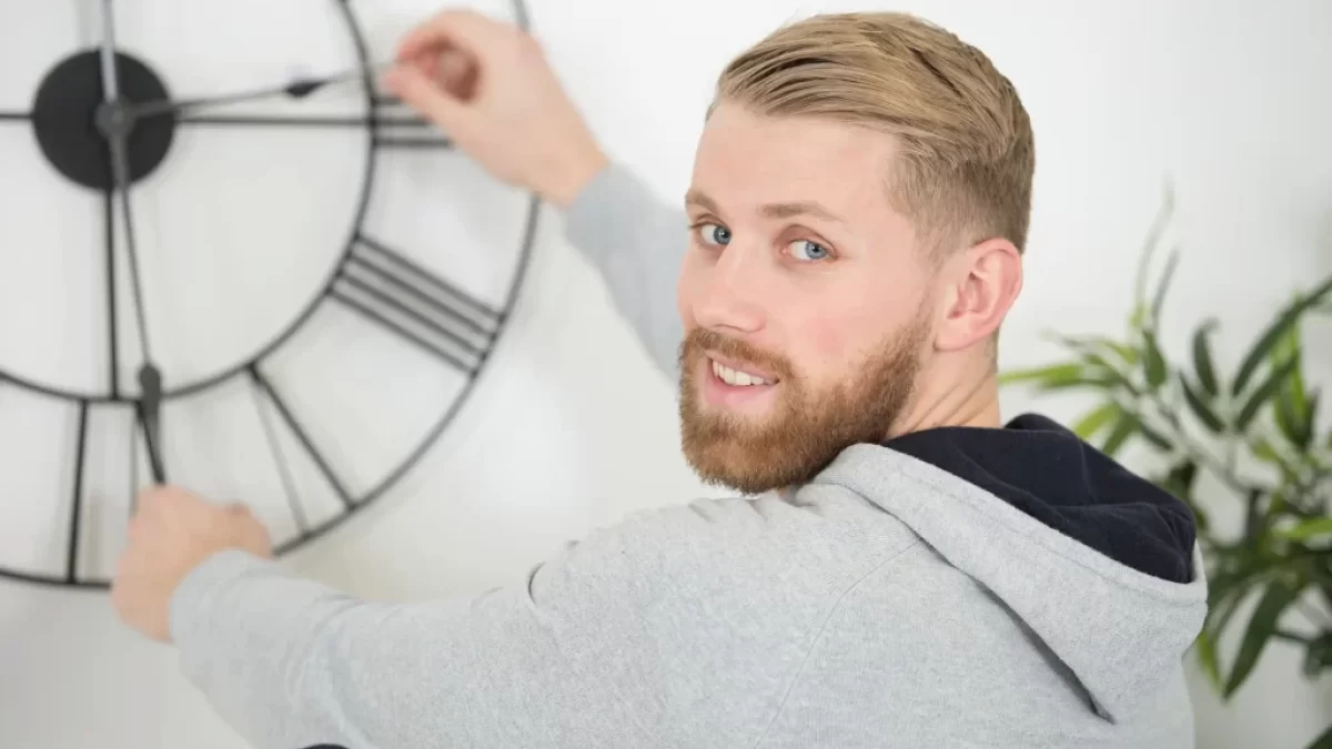 muž přetáčí ručičky na hodinách