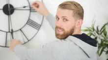 muž přetáčí ručičky na hodinách