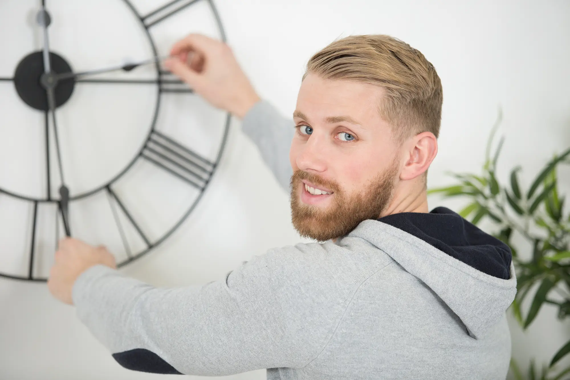 muž přetáčí ručičky na hodinách