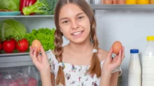 Dívka u lednice drží v ruce vajíčka