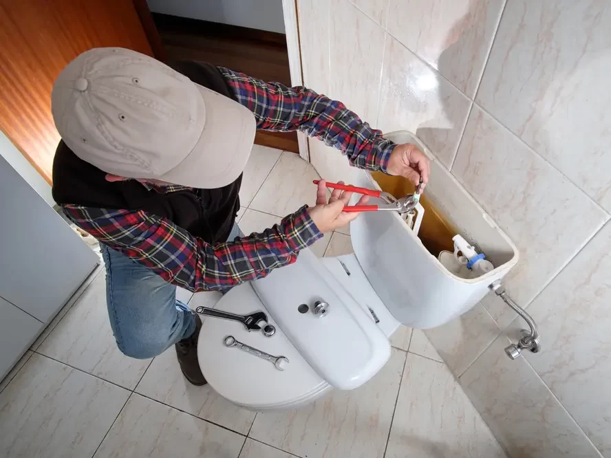 Muž opravuje WC