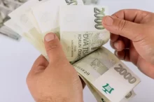 Muž drží v ruce dvoutisícovky