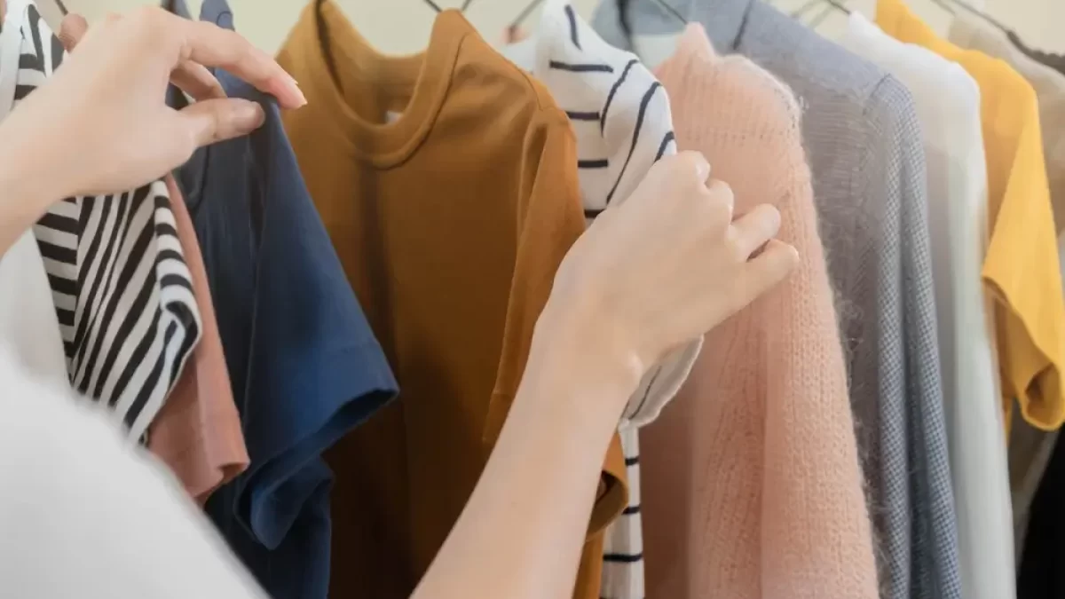 Žena vybírá oblečení z ramínka