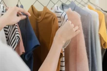 Žena vybírá oblečení z ramínka