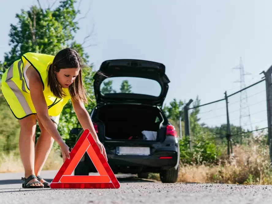 žena dává výstražný trojúhelník za auto