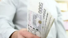 Muž drží pětitisícové bankovky