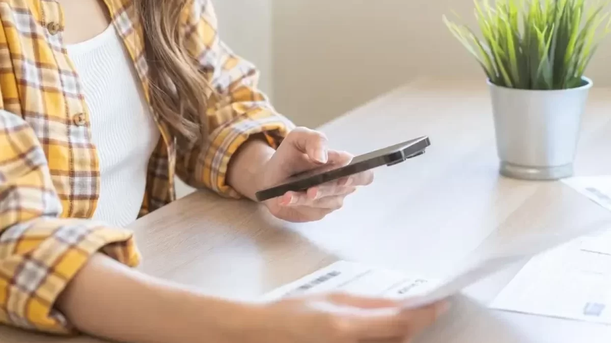 Žena se smartphonem a papírem v ruce
