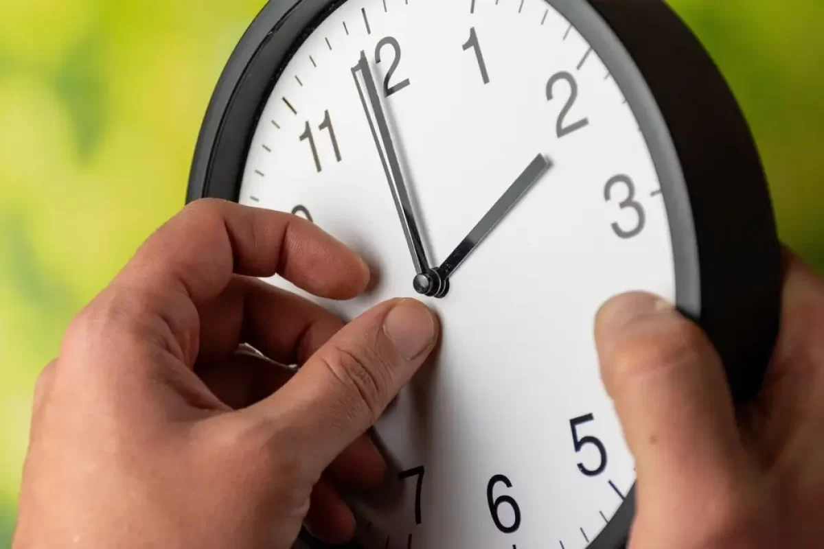 Muž posouvá ručičky na hodinách
