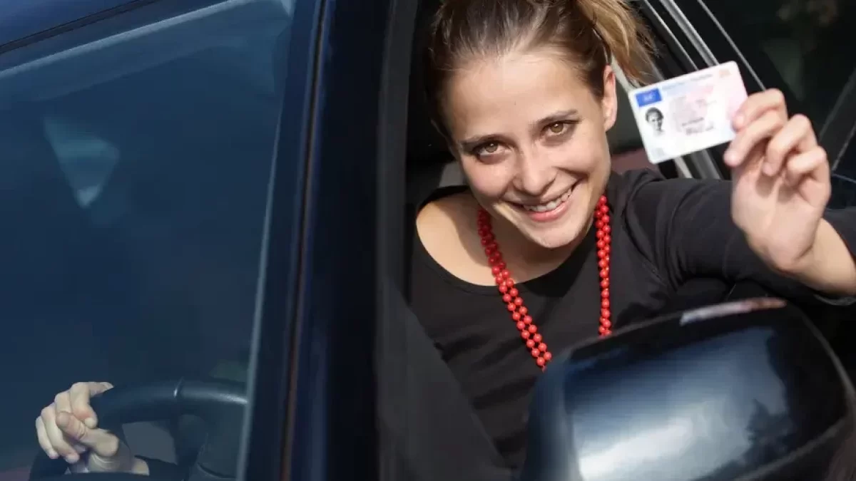 Spokojená žena za volantem ukazující řidičák