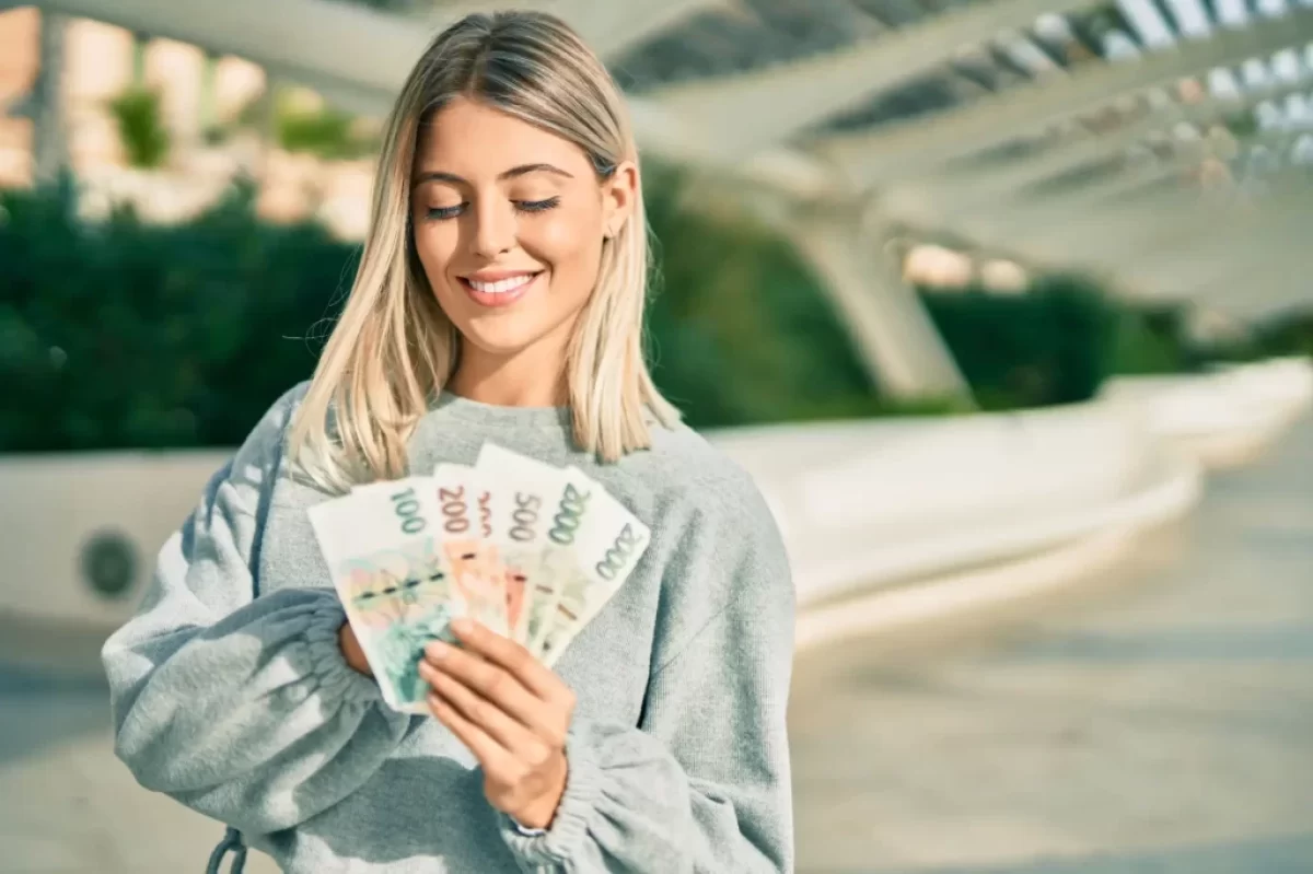 žena drží několik bankovek v ruce