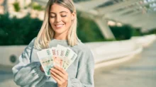 žena drží několik bankovek v ruce