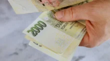 Muž drží v ruce dvoutisícové bankovky