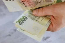 Muž drží v ruce dvoutisícové bankovky