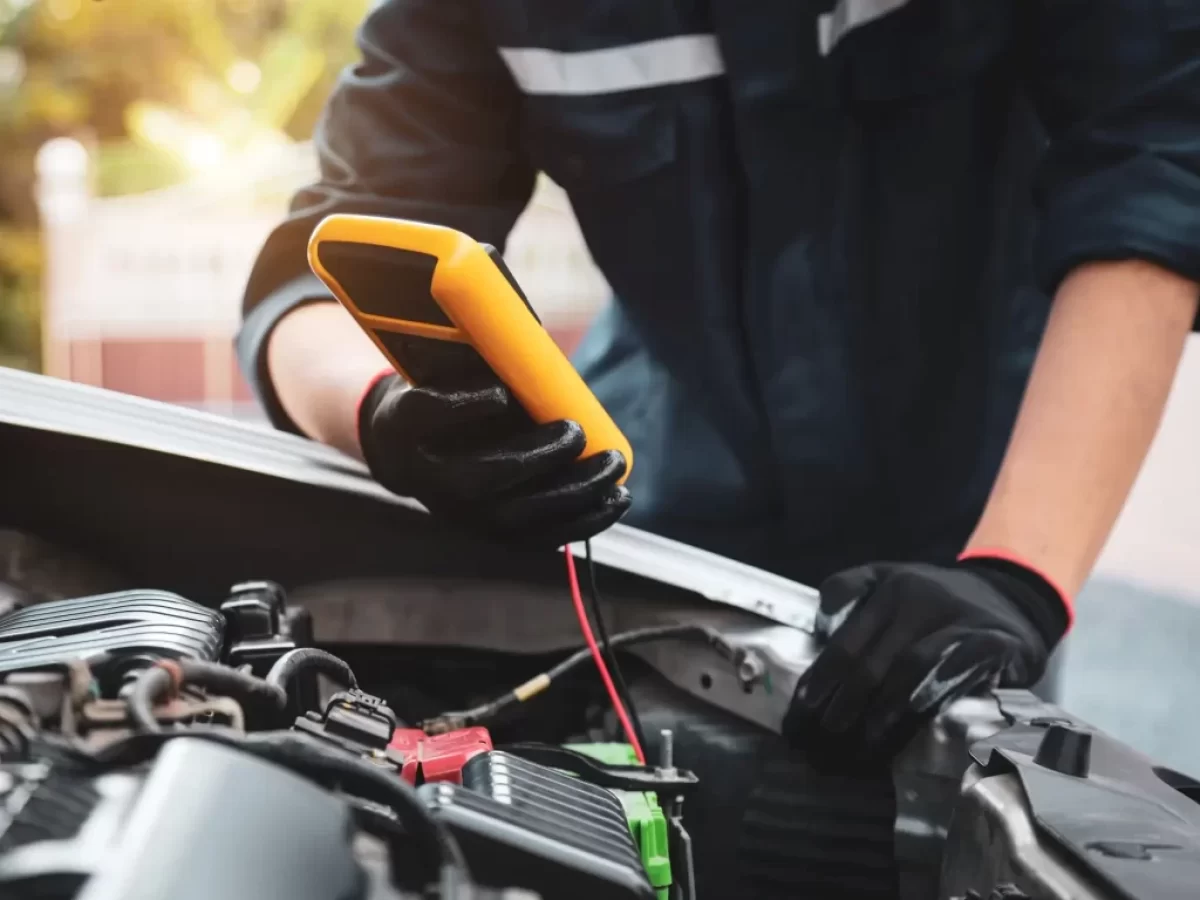 mechanik měří voltáž baterie pomocí multimetru