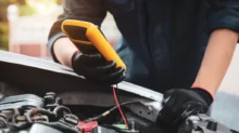 mechanik měří voltáž baterie pomocí multimetru