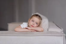 Smutná holčička sedí na gauči