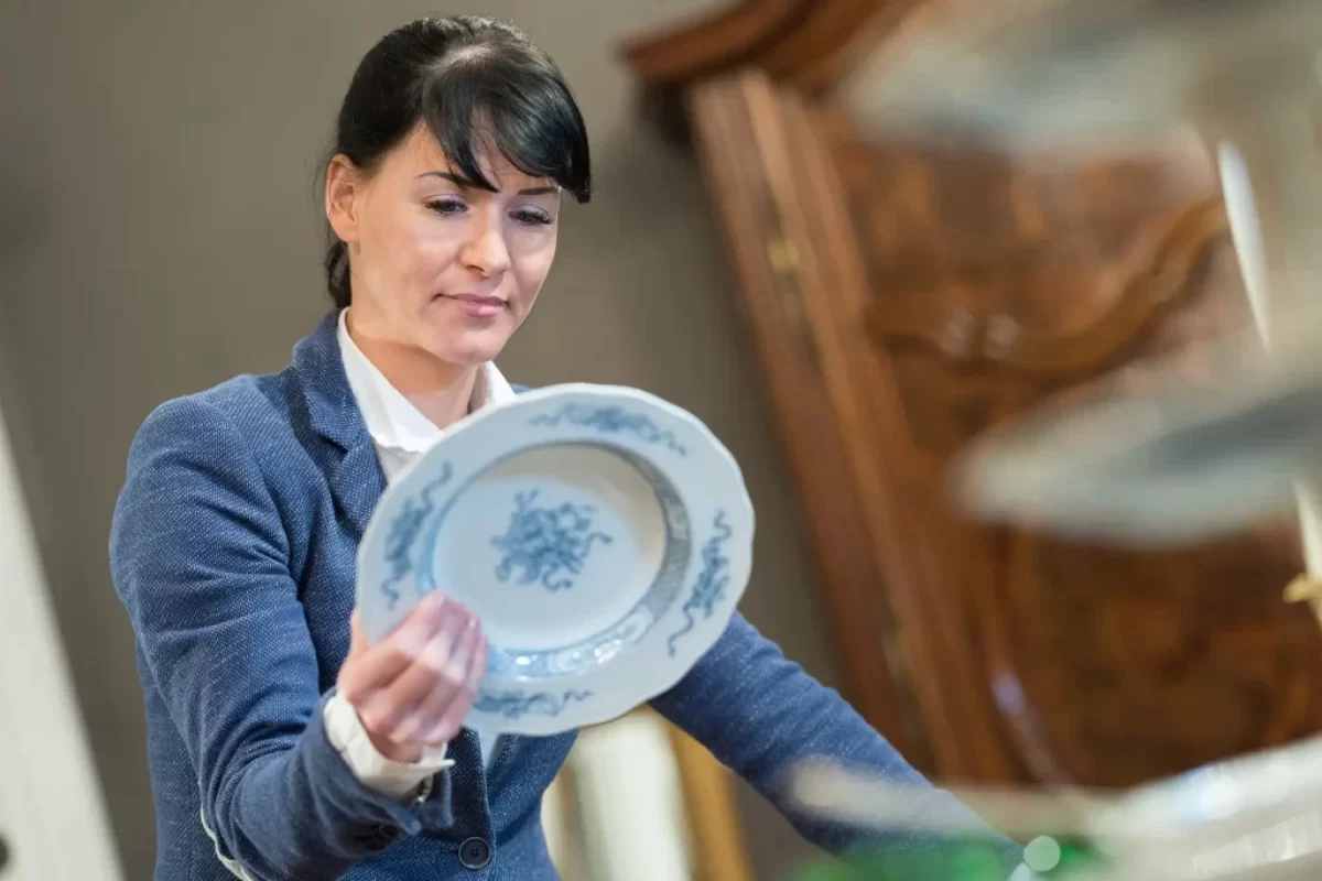 odbornice zkoumá hodnotu porcelánového talíře